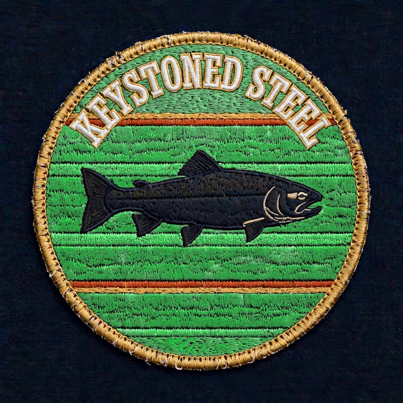 Keystoned Steel Vintage Sunset embroidered patch — oval patch with a black steelhead silhouette over retro green sunset stripes